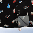 Load image into Gallery viewer, Bottom sweep tag view of the youth short sleeve version of "Got 'Em!" The button down features various athletic fashion sneakers in an 80bit format arranged all over a black shirt. The shirt is featured against a background of a basketball player jumping in air, noticeable sneakers being worn.