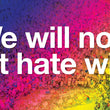 Load image into Gallery viewer, The text "We will not let hate win." in white over a multi-colored rainbow gradient background that is overlaid on a picture of people gathering at a makeshift Pulse Nightclub shooting memorial