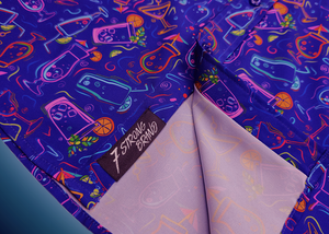 Bottom sweep view of the 7-Strong "Happy Hour" button down shirt, featuring a multitude of neon colored drinks and glassware with garnishes, mixes, and the like all over a deep purple background. The shirt is displayed against a gradient purple background with a neon sign signaling "Happy Hour."