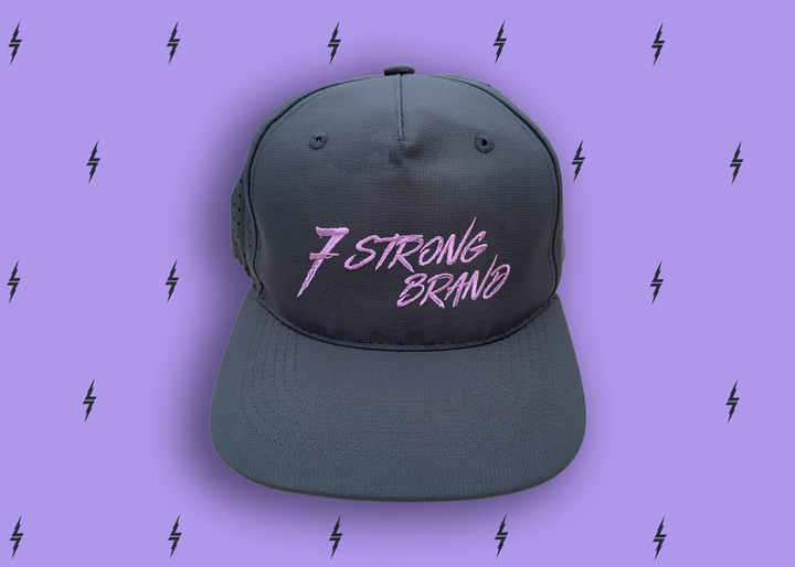 Centered close up of the black 7-Strong script logo hat. The hat is featured a deep lavender background with black 7-bolts patterned throughout. 