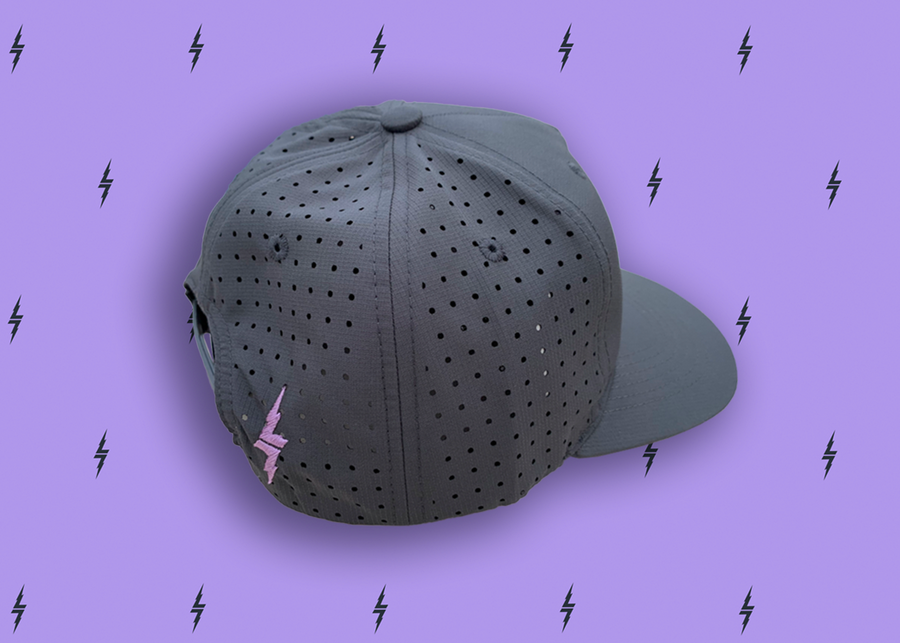 Centered close up of the vented back of the black 7-Strong script logo hat, this view shows it as a snapback and a lavender 7-bolt beside the snap. The hat is featured a deep lavender background with black 7-bolts patterned throughout.