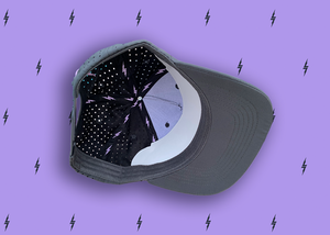 Centered close up of the underside of the black 7-Strong script logo hat, with 7-bolt lining and vented holes. The hat is featured a deep lavender background with black 7-bolts patterned throughout.