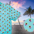 Load image into Gallery viewer, A 3/4 view of the adult 7-Strong &quot;Sunset Palms&quot; shirt, featuring small yellow and pink suns, reminiscent of a sunset, behind a silhouette of a palm tree and birds, patterned at various angles all over the turquoise-like shirt. The shirt is featured against a photo of a palm tree beach at sunset. Bottom right corner features a close up circle detailing the shirt design.  
