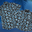 Load image into Gallery viewer, Overlapping full view of the 7-Strong adult and youth Electric Palms shirt, a collection of electric blue palm fronds featured against a black shirt. Shirt is displayed against a scenic beach background. 
