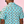 Load image into Gallery viewer, Back, medium view of male model wearing the adult 7-Strong &quot;Sunset Palms&quot; shirt, featuring small yellow and pink suns, reminiscent of a sunset, behind a silhouette of a palm tree and birds, patterned at various angles all over the turquoise-like shirt. The model is featured against a pink tropical backdrop with palm trees in the background. 
