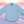 Load image into Gallery viewer, Full centered view view of the baby blue long sleeve EveryWEAR adult button up. Pattern is subtle white 7-Bolts lined up all against each other across a baby blue background. The shirt is featured on a soft background of a wave hitting the beach.
