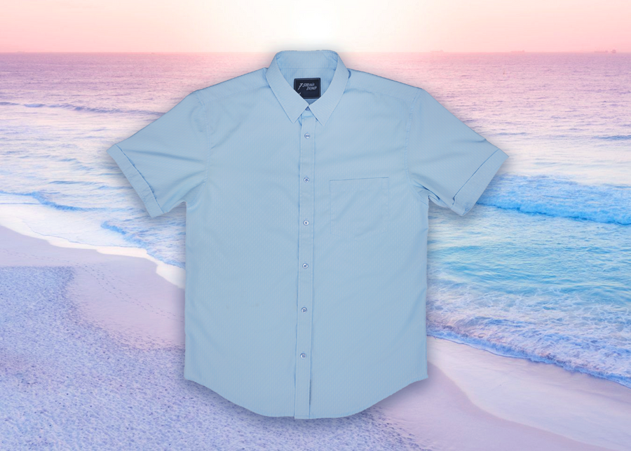 Full centered view of the baby blue short sleeve EveryWEAR adult button up. Pattern is subtle white 7-Bolts lined up all against each other across a baby blue background. The shirt is featured on a soft background of a wave hitting the beach.