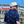 Load image into Gallery viewer, Male model in front of a baseball stadium wearing 7-Strong&#39;s adult Ballpark Blueprints shirt, featuring overhead maps of all the major league stadiums.
