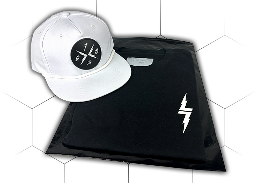 Folded and centered close up of the 7-Strong black Branded tee, featuring a 7-bolt  logo left justifed in white. It is paired with the white "Branded" performance hat with raised x-badge patch. Shirt is featured against a white geometric background.