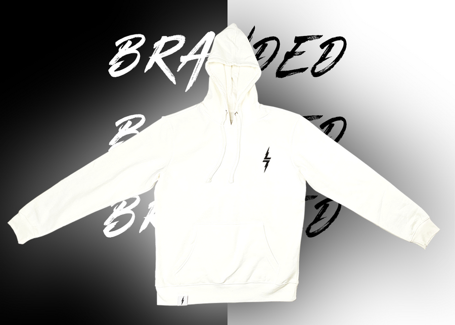 Full centered view of the front of the 7-Strong white 'Branded' hoodie, featuring a black 7-bolt logo on the left chest and a small tag on the hip opening. Shirt is featured against a half black/half white background with the word "BRANDED" written three times down the middle.