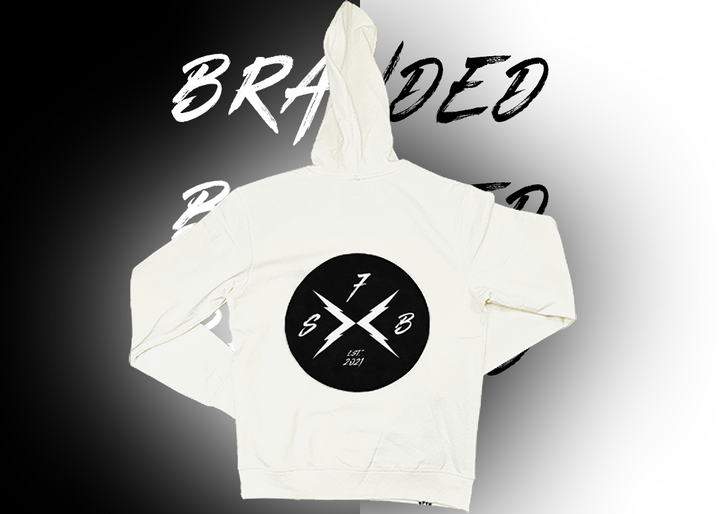 Full centered view of the back of the 7-Strong white 'Branded' hoodie, featuring a circle, badge-like design with two lightning bolts forming an X, and 7-Strong initials and established watermarks.  Shirt is featured against a half black/half white background with the word "BRANDED" written three times down the middle. 
