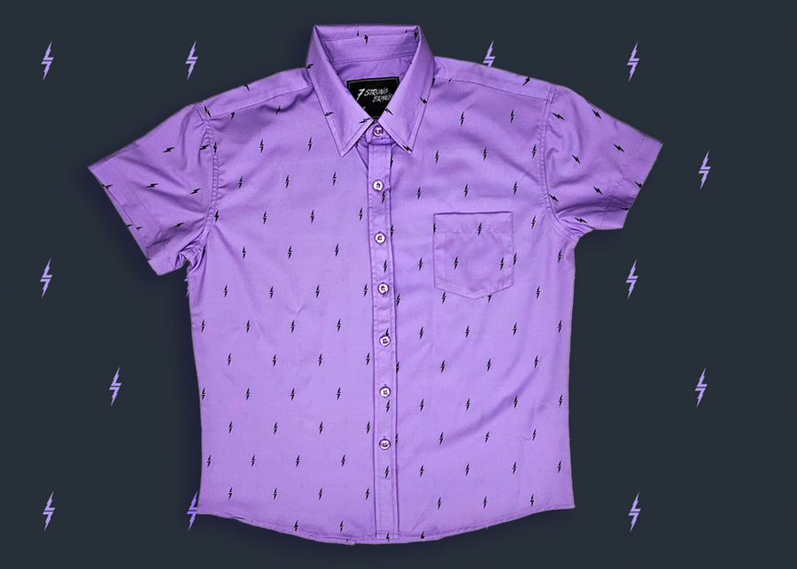 Centered view of the youth 7-Strong Deep Lavender 7-Bolt short sleeve shirt, featuring black 7-bolts interspersed on a deep lavender background. The shirt is featured on a slate backdrop with lavender bolts. 