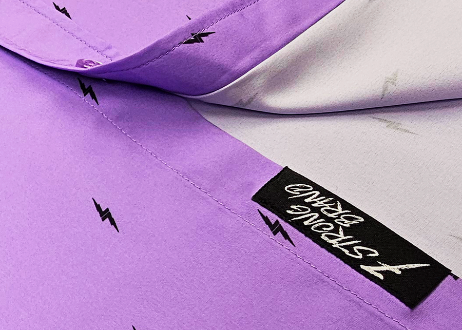 Close up sweep tag view of the 7-Strong Deep Lavender 7-Bolt short sleeve shirt, featuring black 7-bolts interspersed on a deep lavender background.