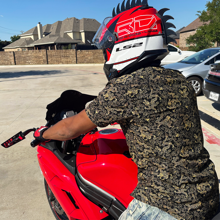 Person wearing a motorcycle helmet and the 7-Strong Bruce Leroy button down featuring gold dragons on a black background, sitting on a red motorcycle in a driveway.