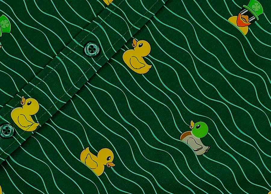 A centered middle view of the 7-Strong "Duck O' The Irish" adult button down, featuring a deep green water-replicating background with various rubber ducks swimming along the waves. 