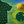 Load image into Gallery viewer, A 3/4 view of the 7-Strong &quot;Duck O&#39; The Irish&quot; adult button down, featuring a deep green water-replicating background with various rubber ducks swimming along the waves. The shirt is featured against a green river scenic with a giant inflatable duck in the background. In the bottom right, there is a detail circle that shows the design pattern up close. 

