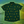 Load image into Gallery viewer, A centered view of the 7-Strong &quot;Duck O&#39; The Irish&quot; youth button down, featuring a deep green water-replicating background with various rubber ducks swimming along the waves. The shirt is featured against a green river scenic with a giant inflatable duck in the background. 
