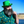Load image into Gallery viewer, A male model standing by the water twirling his beard wearing a green Irish top hat and looking off while wearing the 7-Strong &quot;Duck O&#39; The Irish&quot; adult button down, featuring a deep green water-replicating background with various rubber ducks swimming along the waves. 
