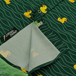 Load image into Gallery viewer, A bottom sweep tag view of the 7-Strong &quot;Duck O&#39; The Irish&quot; adult button down, featuring a deep green water-replicating background with various rubber ducks swimming along the waves. The shirt is featured against a green river scenic with a giant inflatable duck in the background.
