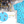 Load image into Gallery viewer, A 3/4 full view of the youth 8-Bit Hat Trick button down - featuring various 8-bit inspired scenes from hockey games on a light blue ice-like background. The shirt is featured against a ice hockey floor with hats strewn about. The bottom left features a detail circle with a close up of a few scenes from the shirt. 
