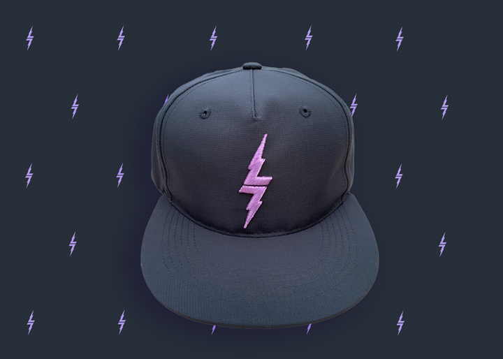 Centered close up of the black 7-Strong 7-bolt logo hat. The hat is featured a slate background with lavender 7-bolts patterned throughout.