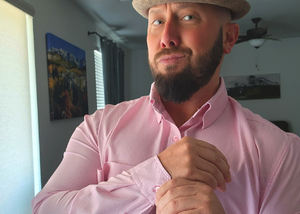 Medium view of a male model gazing into camera wearing the pink long short sleeve EveryWEAR adult button up. Pattern is subtle white 7-Bolts lined up all against each other across a pink background.