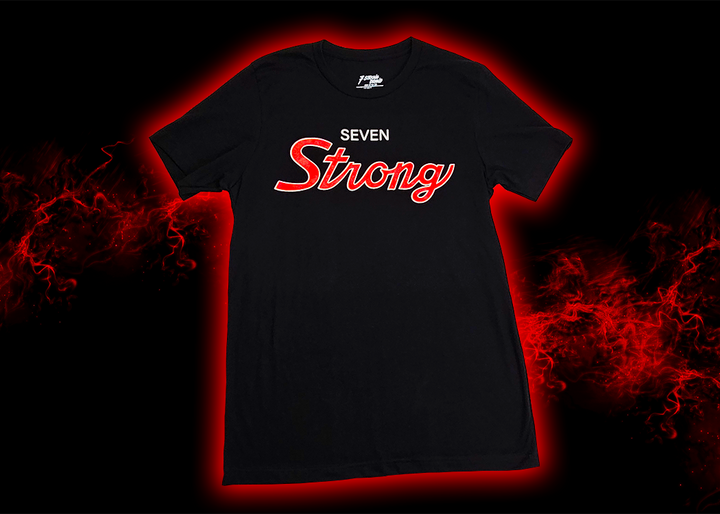 Full look at the Black 7-Strong Sideline Script tee, with white SEVEN and red scripted STRONG across the chest. Shirt is on the back of a red and black fusion background. 