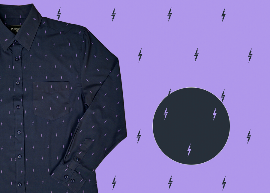 3/4 view of the 7-Strong Slate 7-Bolt long sleeve shirt, featuring lavender 7-bolts interspersed on a slate gray background. The shirt is featured on a lavender backdrop with black bolts. The bottom left features a detail circle showing the 7-bolt design up close.