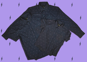 Centered, overlapping view of the adult and youth 7-Strong Slate 7-Bolt short sleeve shirt and adult long sleeve shirt, featuring lavender 7-bolts interspersed on a slate gray background. The shirt is featured on a lavender backdrop with black bolts