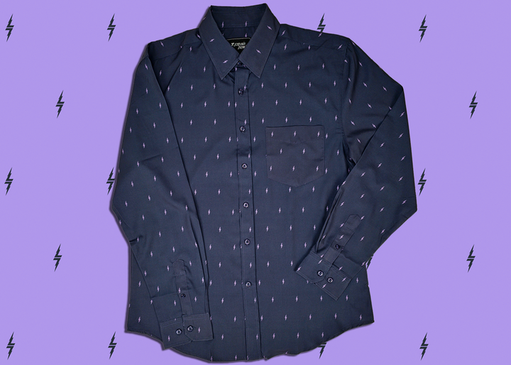 Centered, full view of the 7-Strong Slate 7-Bolt long sleeve shirt, featuring lavender 7-bolts interspersed on a slate gray background. The shirt is featured on a lavender backdrop with black bolts