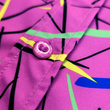 Load image into Gallery viewer, A midsection button view of the 7-Strong youth &quot;Strongfetti&quot; button down, a bold pink shirt featuring black, yellow, lime green, and navy blue scratches that appear like confetti falling from the sky. The shirt is featured on a white background with colorful falling confetti.
