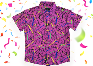 A full, centered view of the 7-Strong youth "Strongfetti" button down, a bold pink shirt featuring black, yellow, lime green, and navy blue scratches that appear like confetti falling from the sky. The shirt is featured on a white background with colorful falling confetti.