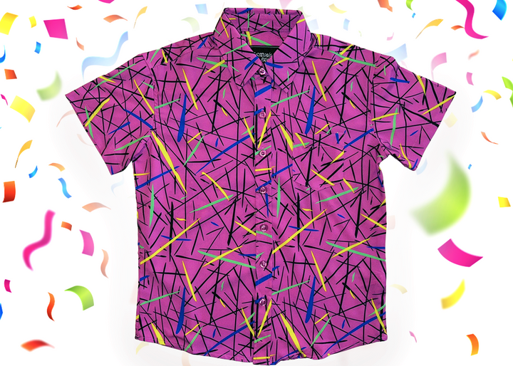A full, centered view of the 7-Strong youth "Strongfetti" button down, a bold pink shirt featuring black, yellow, lime green, and navy blue scratches that appear like confetti falling from the sky. The shirt is featured on a white background with colorful falling confetti.