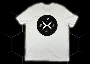 Centered full view of the back of the 7-Strong white Branded tee, featuring the X-Brand patch logo centered in black. Shirt is featured against a black geometric background.