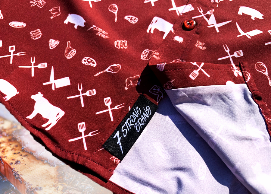 A bottom sweep tag view of the 7-Strong youth "Smoke Show" button up, a deep maroon red colored shirt with rows of various barbecue and cookout related items and delicacies silhouetted in white.