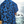 Load image into Gallery viewer, Back view of a youth model wearing the 7-Strong youth Electric Palms shirt, a collection of electric blue palm fronds featured against a black shirt. Model is displayed against an overlook of a scenic beach.
