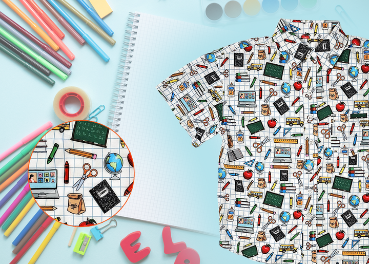 Offcentered view of 7-Strong Class Act  youth button-down featuring various classroom items such as pencils, rulers, globes, notebooks, apples, protractors, etc against a white graph paper background. Shirt is against a background of school supplies.  Bottom left features a detail circle showing a close up of some of the items on the shirt. 