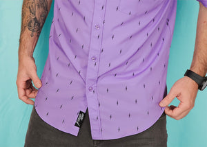 Lower torso view a male model against a teal background wearing the 7-Strong Deep Lavender 7-Bolt short sleeve shirt, featuring black 7-bolts interspersed on a deep lavender background. 