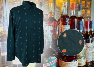 Full display view of the 7-Strong "Straight Sippin'" long Sleeve button down. The shirt is a deep green with black ripples as its background, while the foreground has various drinking glasses with various levels of whiskey, some with ice, others without. The shirt is shown against a background of various whiskies and bourbons on a shelf. In the right corner, there is a detail circle showcasing the shirt's glass designs, up close.