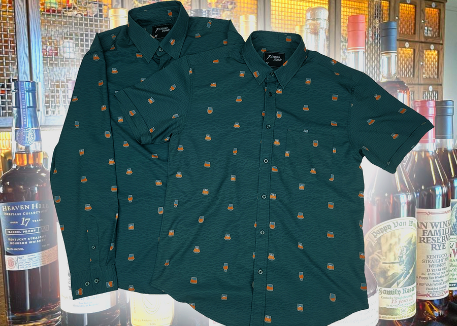 Full display view of the 7-Strong "Straight Sippin'" long sleeve and short sleeve button downs overlapping each other. The shirt is a deep green with black ripples as its background, while the foreground has various drinking glasses with various levels of whiskey, some with ice, others without. The shirt is shown against a background of various whiskies and bourbons on a shelf.