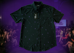 Full view of the 7-Strong "Flux Capacity" short sleeve button down, showcasing bursts and lines of purple light peering through a black grid of cubes. The background is of a fashion show runway in purple hue. 