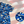 Load image into Gallery viewer, 3/4 Full view close up of the 7-Strong &quot;Service Stars&quot; Adult button-up, featuring blue and creme colored camouflage with white weathered stars throughout. The shirt is featured against a waving U.S. Flag faded into the background. Top right is the 22 Flag Co logo, bottom left is a detail circle showing a close up of the camouflage and star design. 
