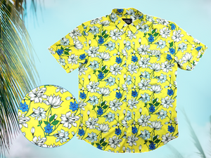 Full view of the 7-Strong "Late Bloomer" adult button down - a yellow background shirt with white and blue flowers patterned all over it. Shirt is against a blue tropical sky with palm trees in the distance. Bottom left of photo has a detail circle which showcases the flowers on the shirt. 