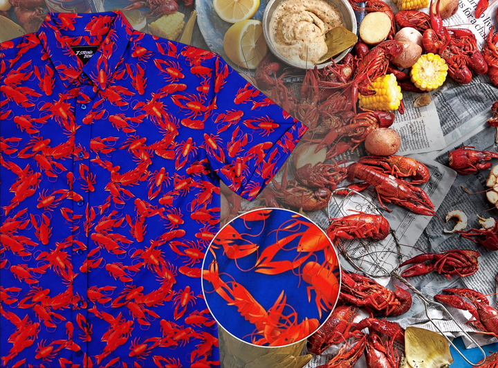 Full view of the adult 7-Strong Dat Boil shirt, with design circle in center, showing off details of deep navy blue with red crawfish patterned throughout overlapping one another. The shirt itself sits on a background image of items from a Crawfish Boil such as crawfish, seasoning, corn, and potatoes. 