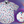 Load image into Gallery viewer, Full view of the 7-Strong Block Party adult button down, featuring various colored blocks of different arrangements inspired by a classic video game, cascading down the shirt against a grayish background featuring shadows of the same shapes. The shirt is presented on a background of similar design.In the bottom right is a detail circle with a close up of the design. 
