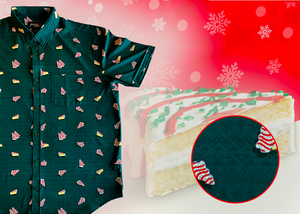 3/4 full view of the 7-Strong "Oh, Christmas Treat" shirt - a green, christmas sweater-like background with columns of various white Christmas tree shaped cakes with red garland, some whole, some bitten. The shirt is displayed against a red, snowing background with a similar parted cake. Bottom right shows a detail circle highlighting the subtle shirt design. 