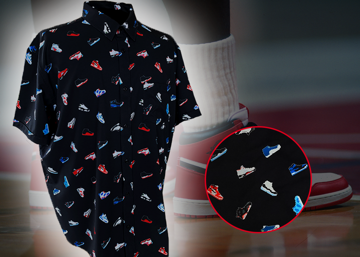 Full view of the adult short sleeve version of "Got 'Em!" The button down features various athletic fashion sneakers in an 8-bit format arranged all over a black shirt. The shirt is featured against a background of a basketball player on the court, noticeable sneakers being worn. Bottom right corner features a detail circle showing the various shoes up close.