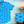Load image into Gallery viewer, 3/4 view of the 7-Strong &quot;Pennant to Win It&quot; shirt, which is sky blue with texture, featuring various triangular flags featuring baseball&#39;s prominent cities patterned throughout. The shirt is featured against abackground is sunset at a major league stadium. The bottom right corner feature a close-up circle showing details of the pennant flags featured on the shirt. 
