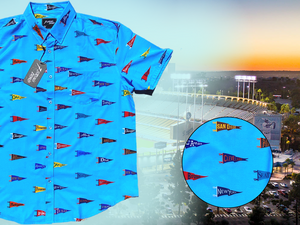 3/4 view of the 7-Strong "Pennant to Win It" shirt, which is sky blue with texture, featuring various triangular flags featuring baseball's prominent cities patterned throughout. The shirt is featured against abackground is sunset at a major league stadium. The bottom right corner feature a close-up circle showing details of the pennant flags featured on the shirt. 