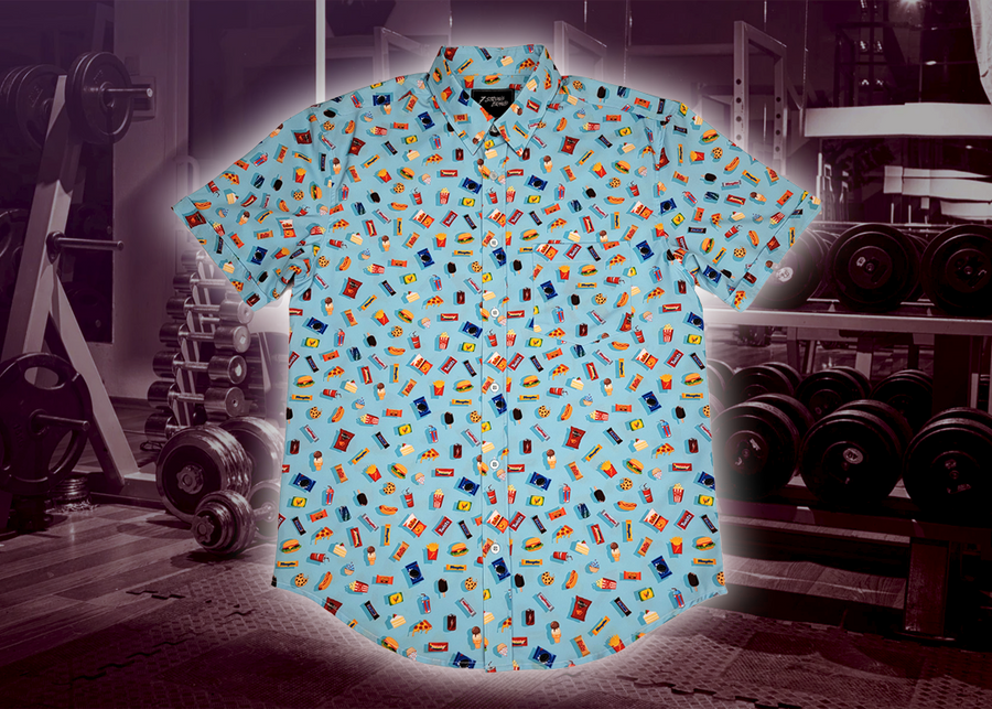 Full view of the 7-Strong "Cheat Day" adult button down featuring various snacks, treats, and fast food features on a light blue shirt. The shirt is displayed against a background of a gym weight rack.